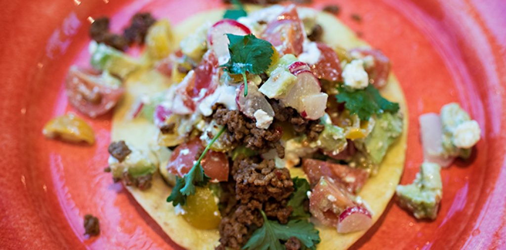 Stekt tortilla toppad med färs, röda och gula tomater, rädisor, avokado och fetaost