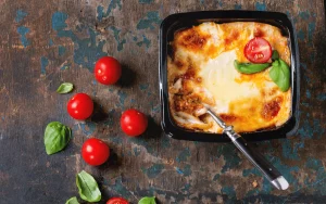 Klassisk lasagne al forno i form med gratinerad ost, basilika och färska tomater